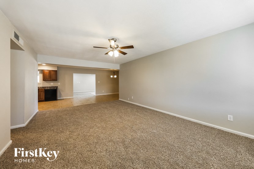 a spacious living room with carpet and a ceiling fan