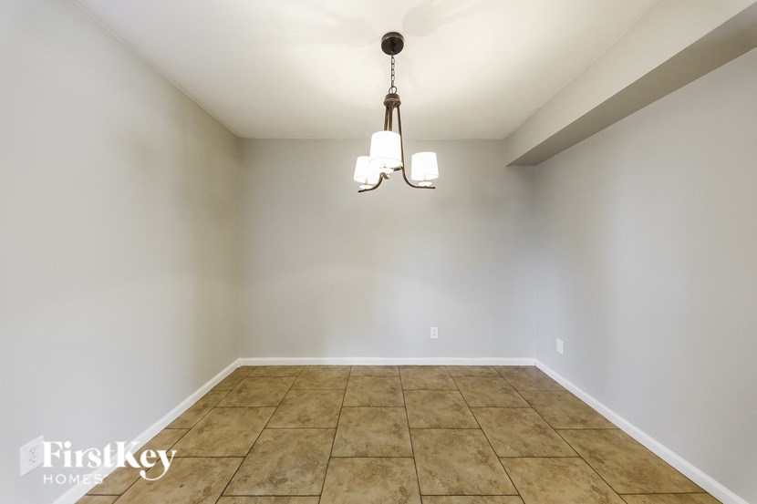 a empty dining room with tile floors and a chandelier