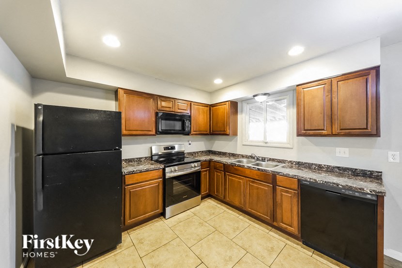 a kitchen with wooden cabinets and black appliances and tiled floors