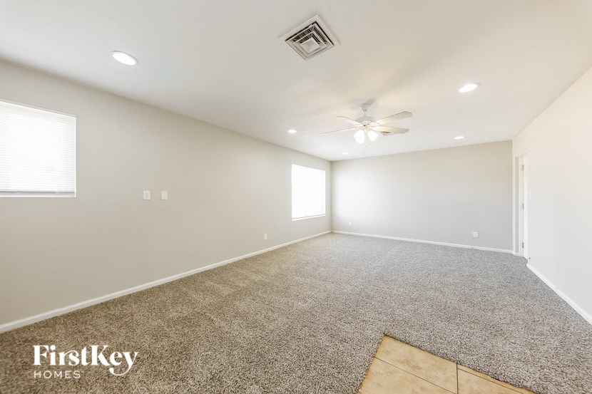 a spacious living room with carpet and a ceiling fan