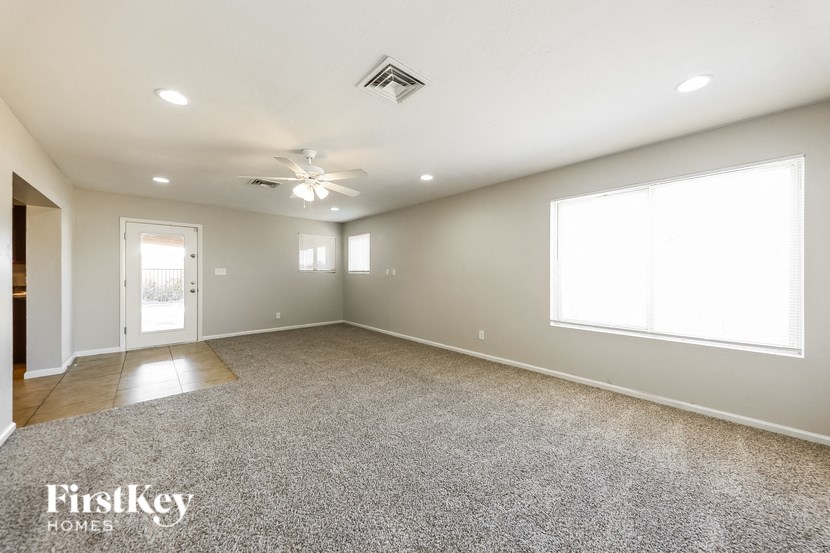 a spacious living room with carpet and a ceiling fan