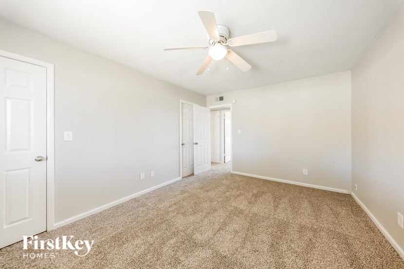a spacious living room with carpet and a ceiling fan