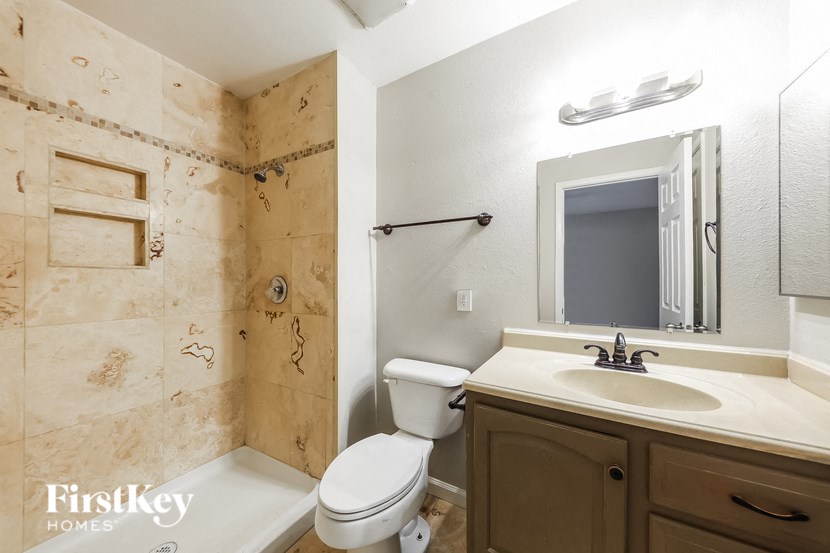 a bathroom with a toilet sink and shower and a mirror