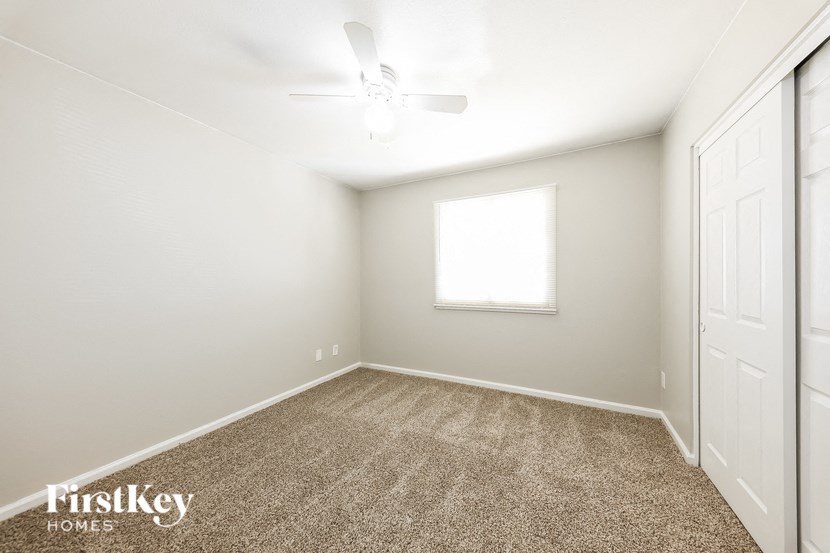 a room with carpet and a window and a ceiling fan