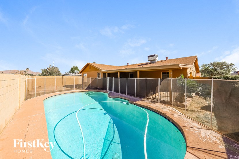 a swimming pool in front of a house with a fence