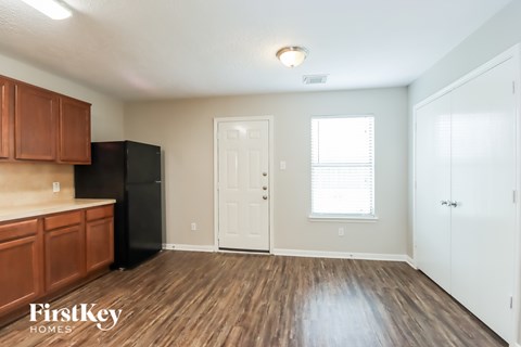 A kitchen with wooden cabinets and a black fridge.