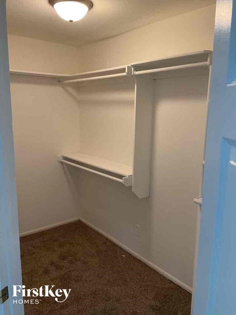 a walk in closet with a shelf in it