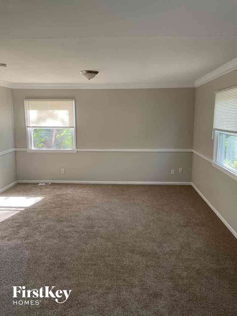 an empty room with carpet and two windows