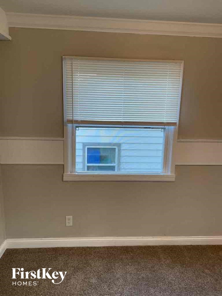 a window with white blinds in a room with beige walls