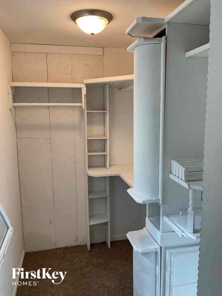a walk in closet with shelves and a desk