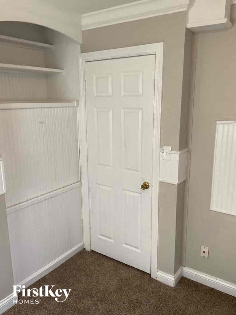 a closet with a white door and a white wall with shelves