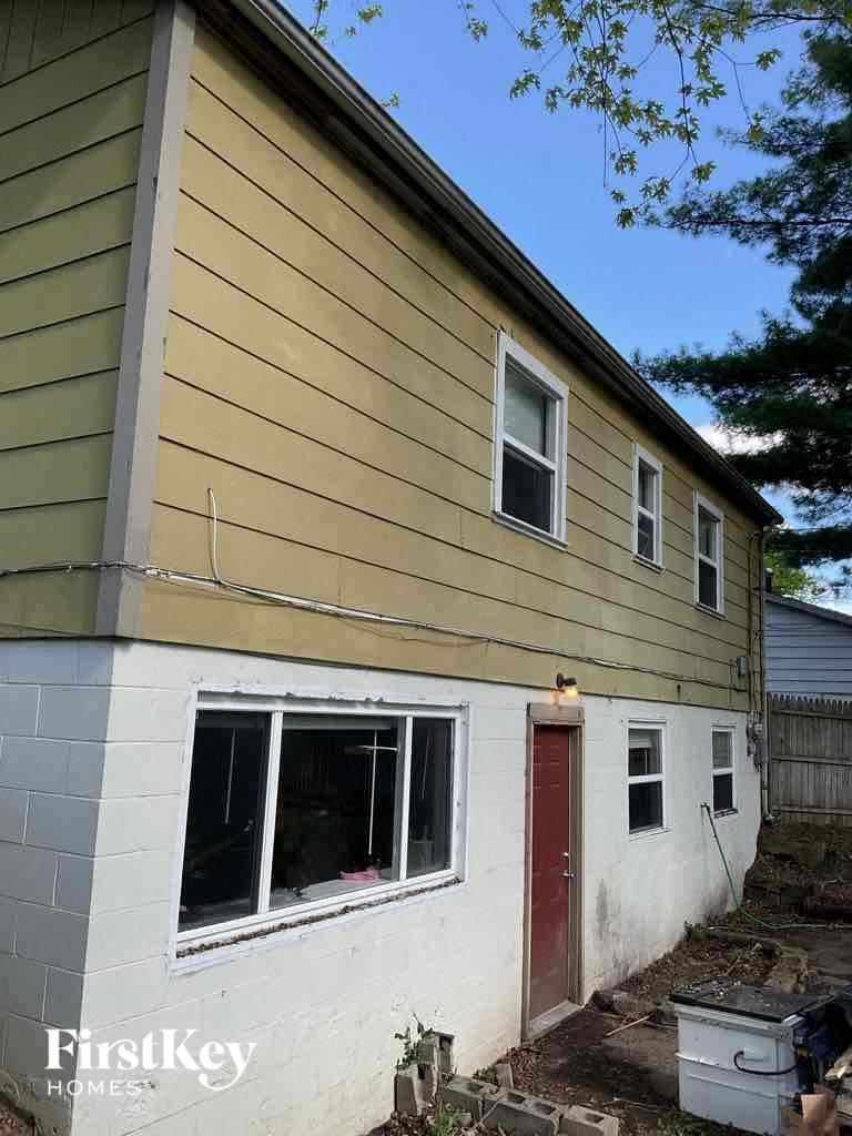 the side of a house with a red door and yellow siding