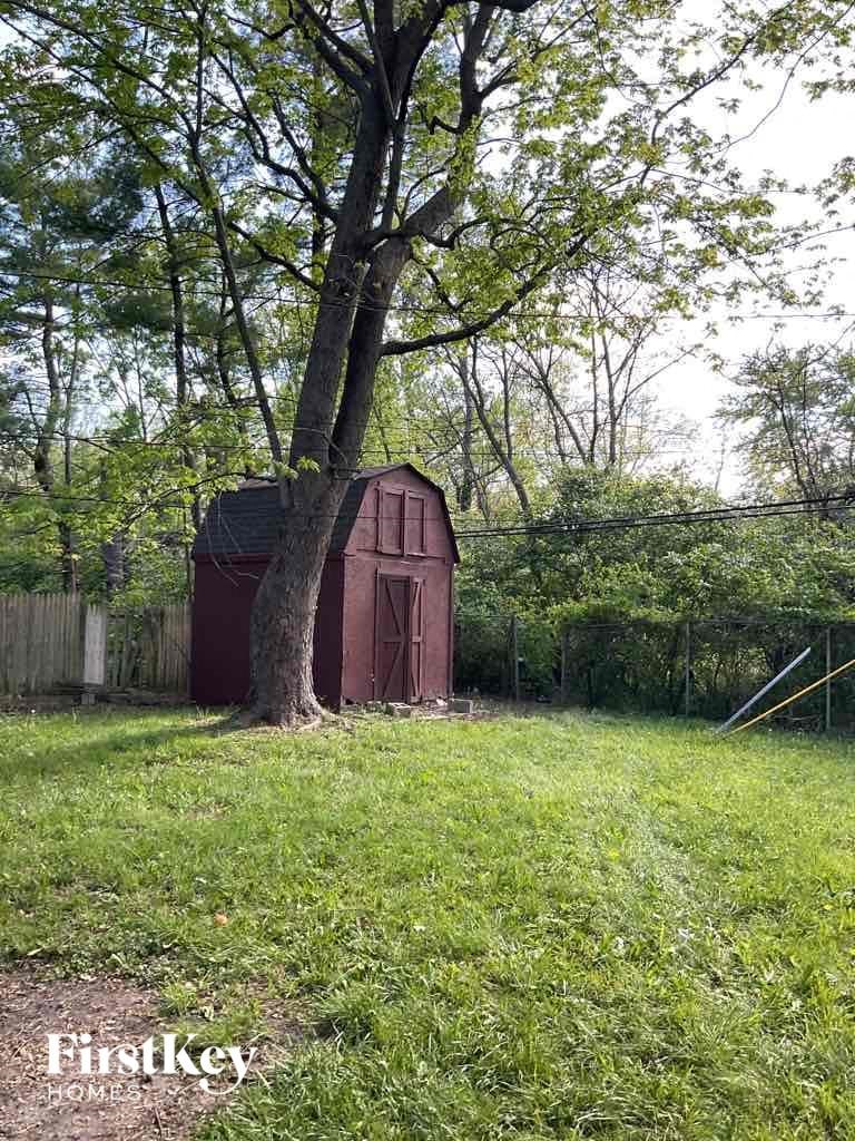 a small red barn in a field next to a tree