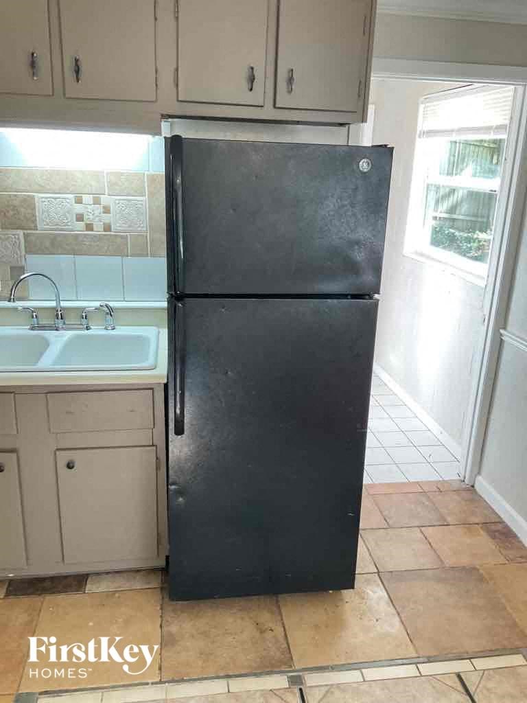 a black refrigerator in a kitchen next to a sink