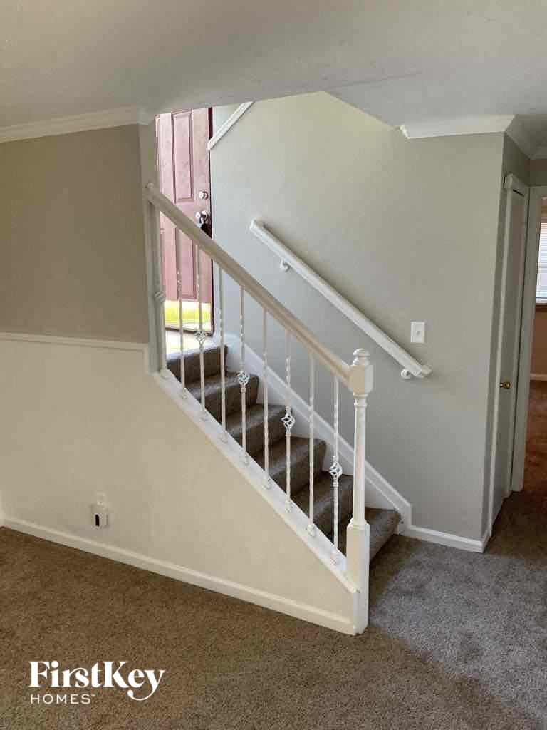 a stairwell in a home with a white railing and a carpeted floor