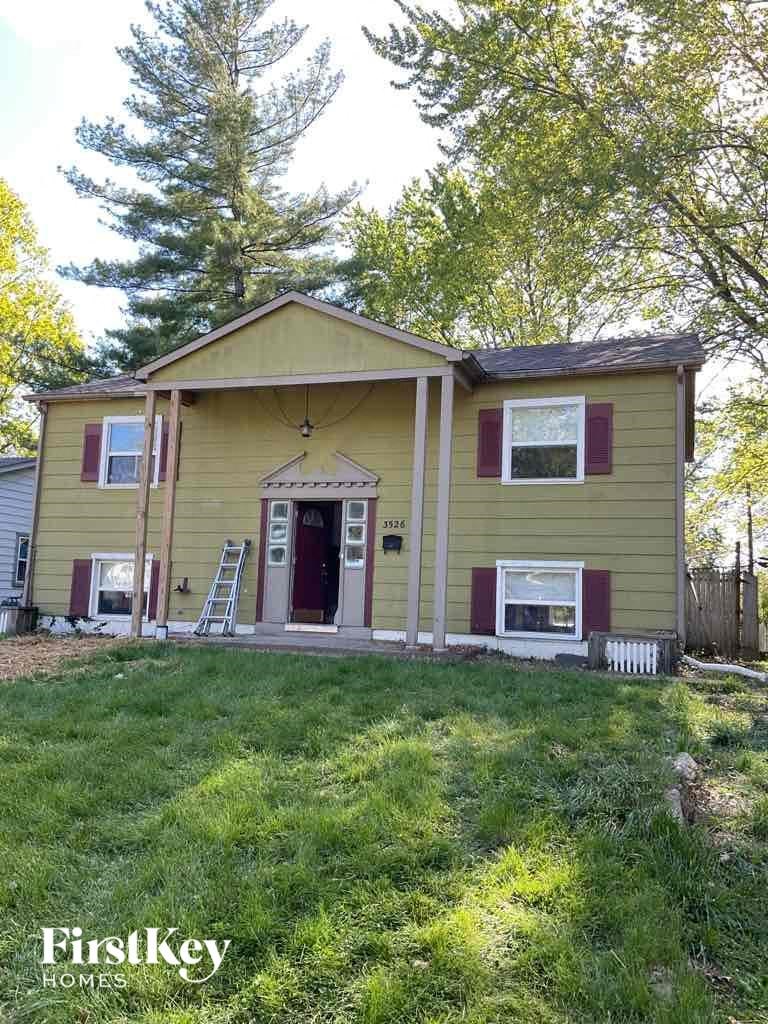a yellow house with a red door and a lawn