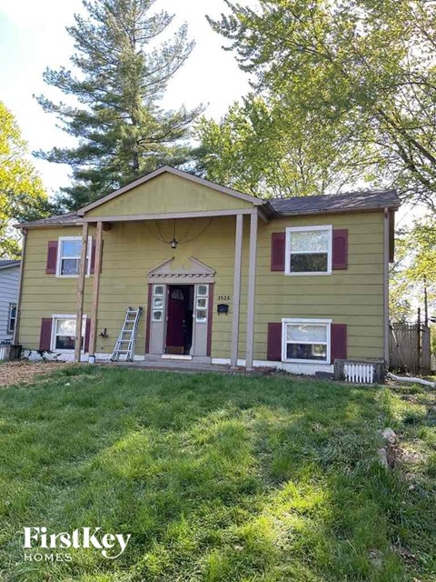 a yellow house with a red door and a lawn