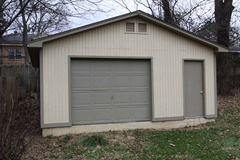 a white garage with a gray garage door on the side of it