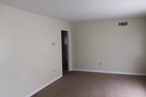 an empty living room with white walls and a door to a hallway