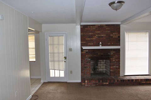 an empty living room with a brick fireplace