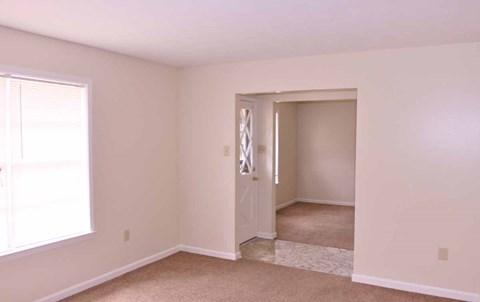 an empty living room with a door to a bedroom