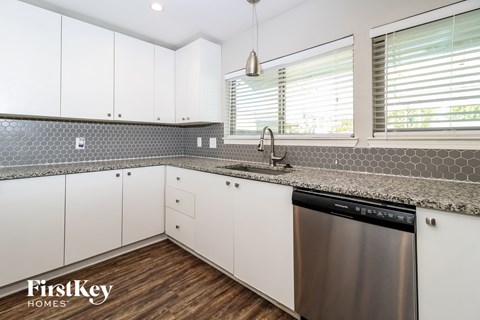 A modern kitchen with a stainless steel dishwasher and white cabinets.
