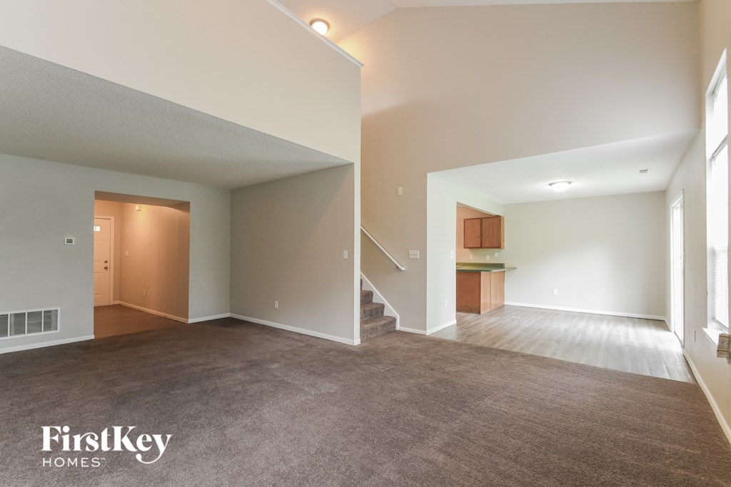 A spacious living room with a staircase leading to the upper floor.