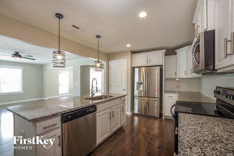 A kitchen with a stainless steel refrigerator and a granite countertop.