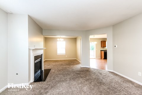 A spacious living room with a fireplace and carpeted floor.