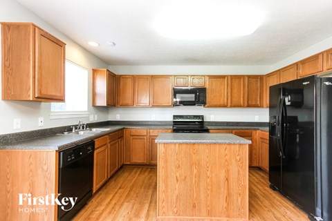 A kitchen with wooden cabinets and a black fridge.