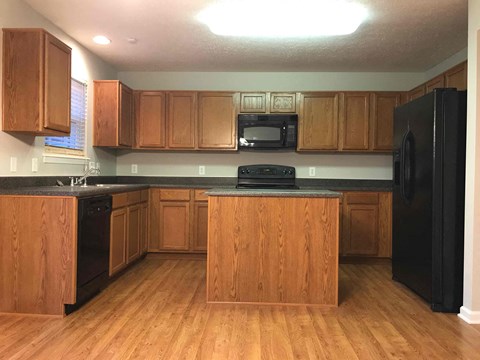 A kitchen with wooden cabinets and black appliances.