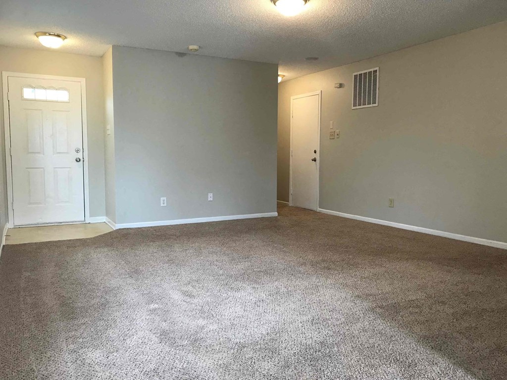an empty living room with carpet and a door