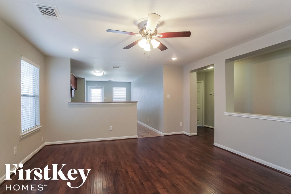 A spacious room with a ceiling fan and wooden flooring.