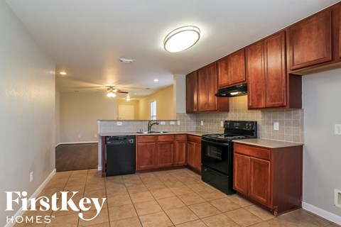 A kitchen with brown cabinets and a black dishwasher.