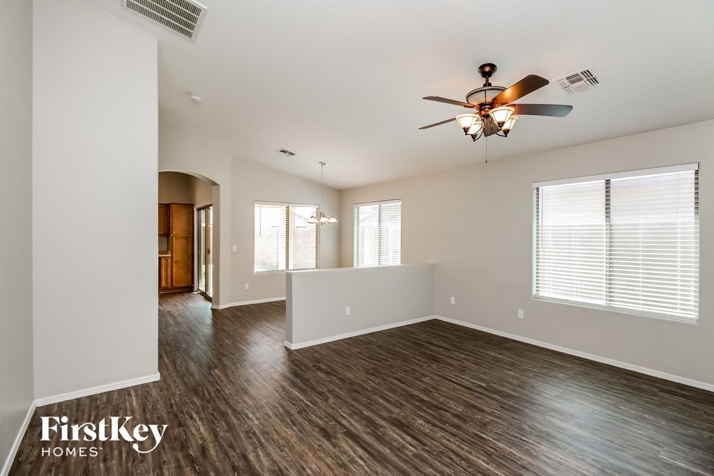 the living room and dining room of an empty house with a ceiling fan