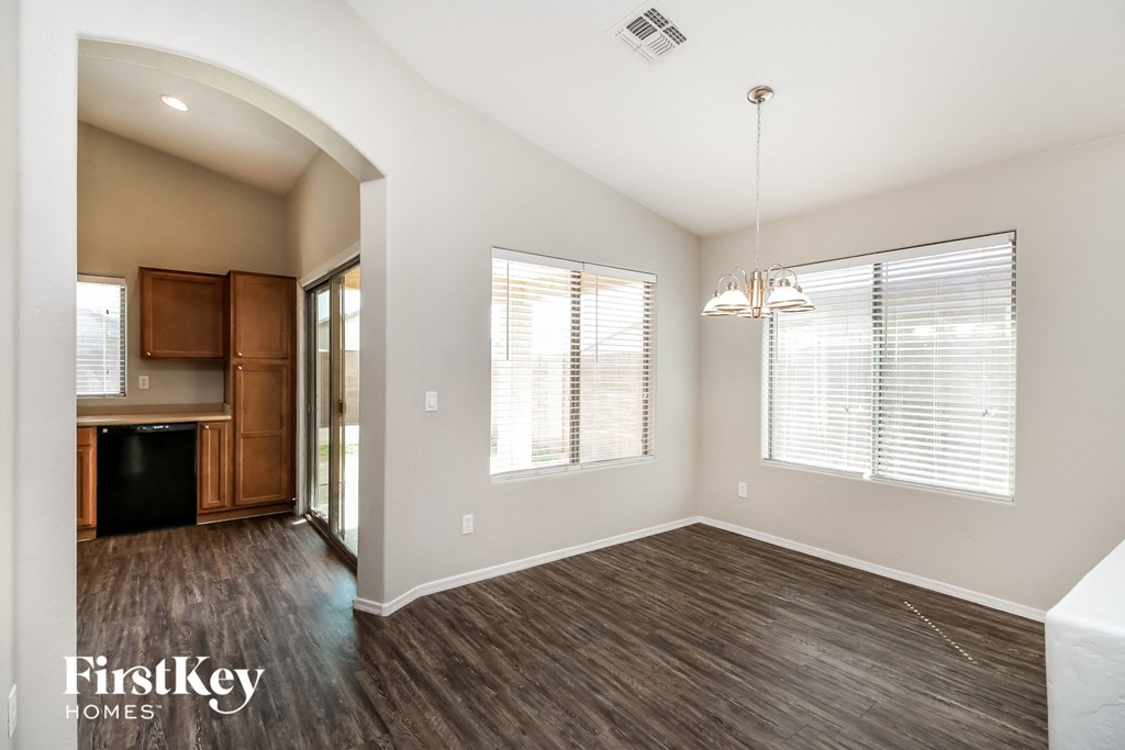 an empty living room with wood flooring and a kitchen