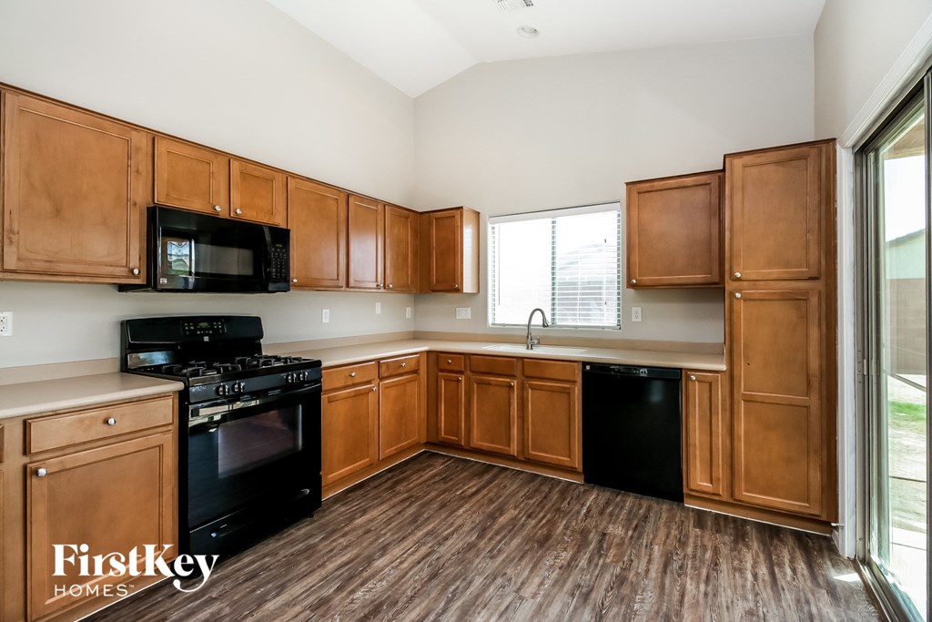 an empty kitchen with wooden cabinets and black appliances