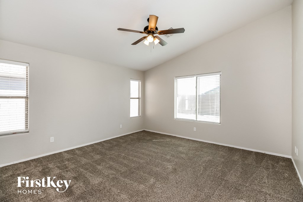 an empty living room with a ceiling fan and two windows