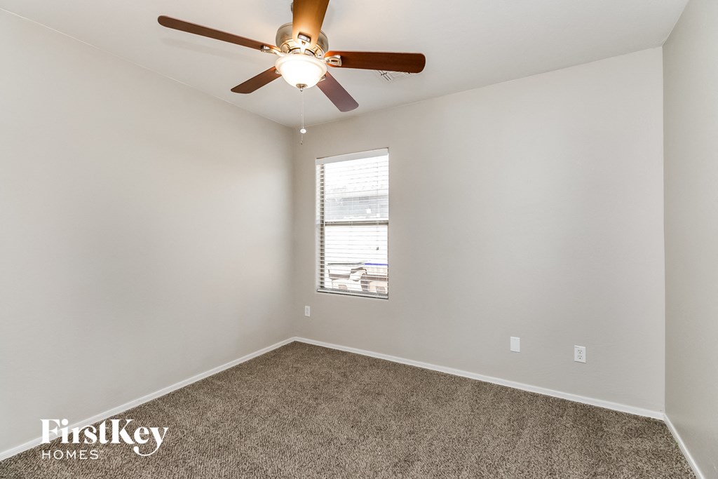 an empty room with a ceiling fan and a window