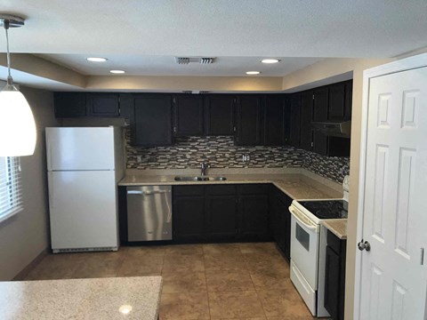 a kitchen with black cabinets and a white refrigerator