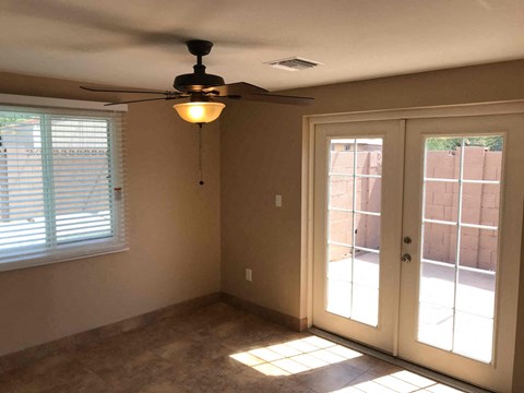 a living room with a ceiling fan and a door to a patio