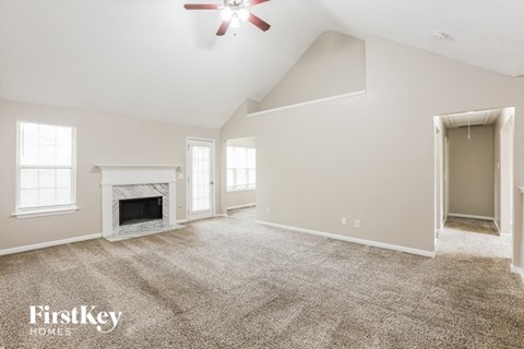 a spacious living room with carpet and a fireplace