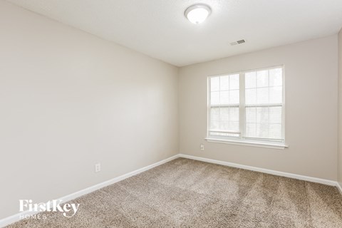 a spacious room with carpet and a window
