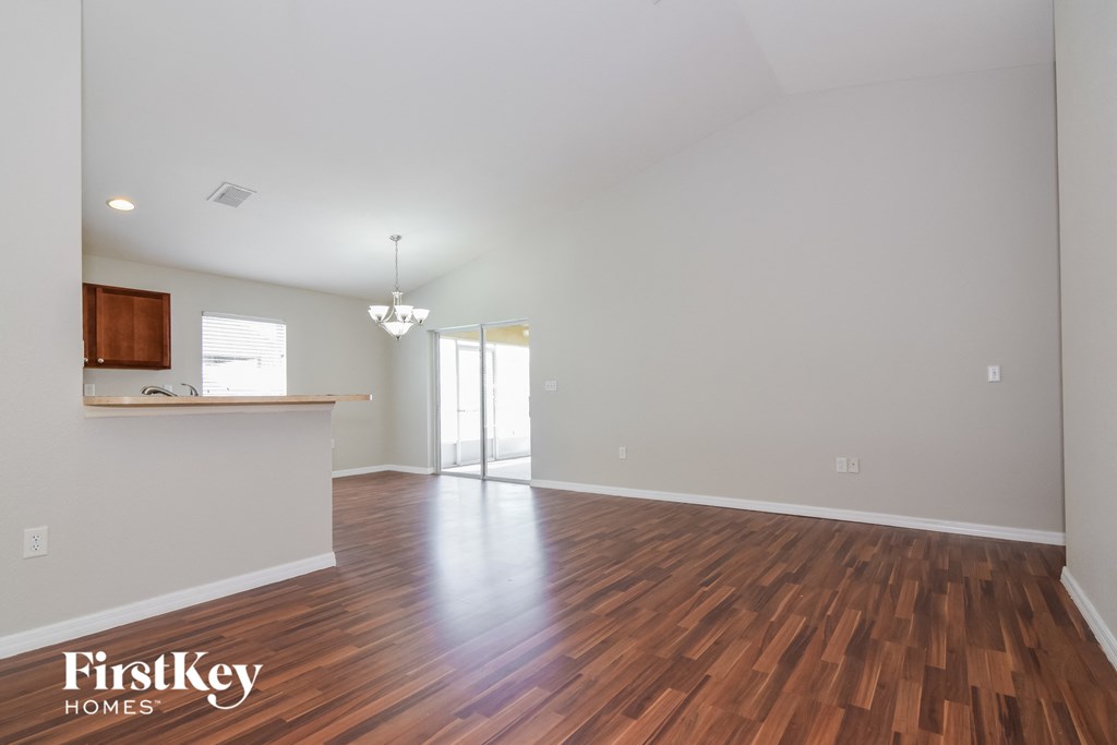 the living room and kitchen of an empty house with wood flooring