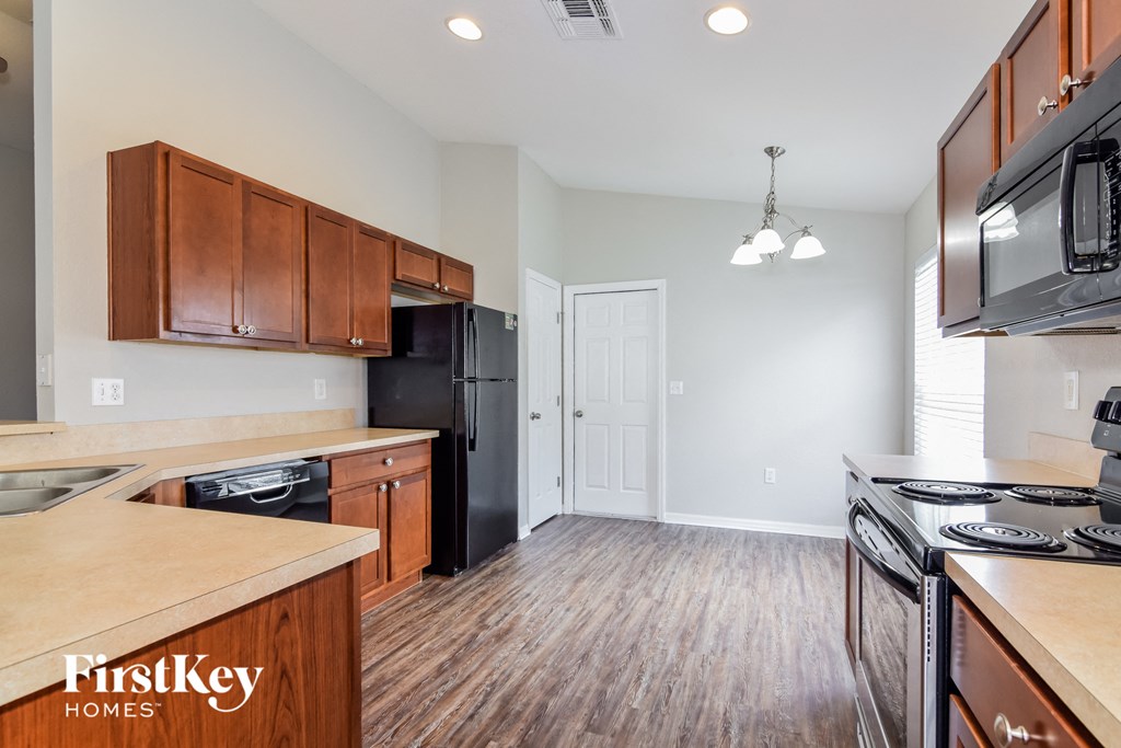 an empty kitchen with wood flooring and black appliances