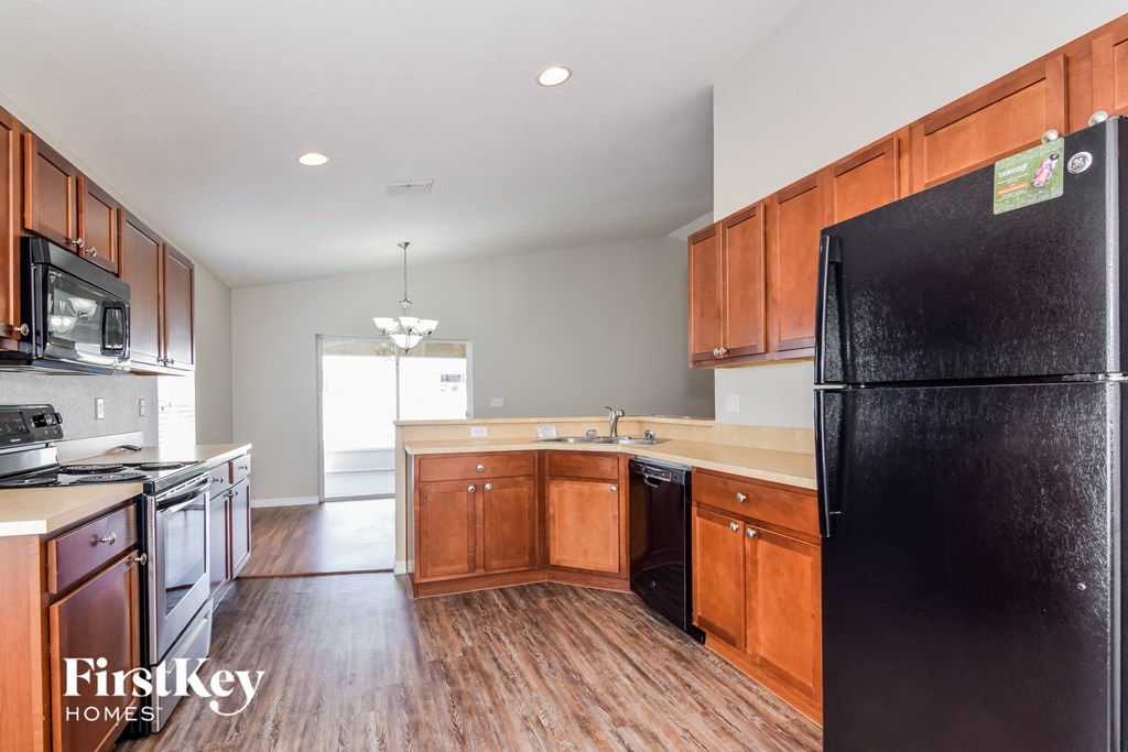 a kitchen with wooden cabinets and a black refrigerator