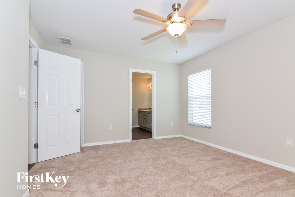a bedroom with a ceiling fan and a door to a bathroom