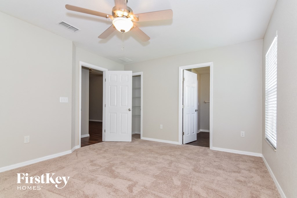 an empty living room with a ceiling fan and a closet
