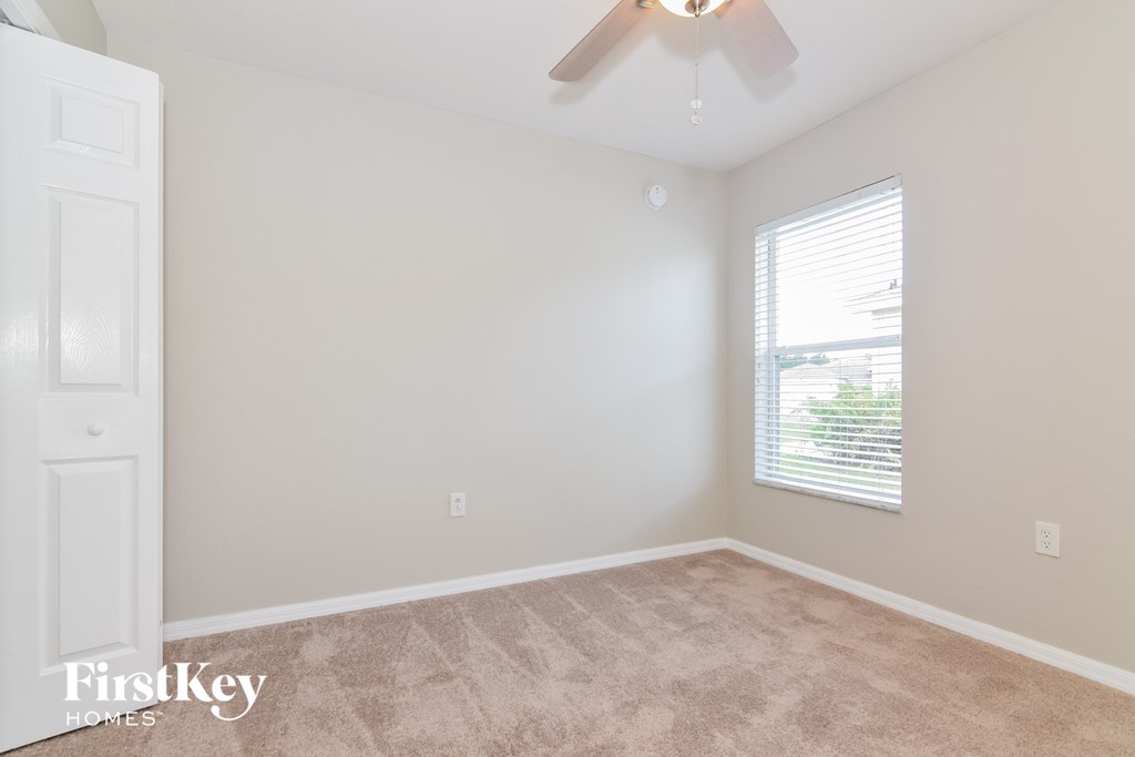 an empty room with a ceiling fan and a window