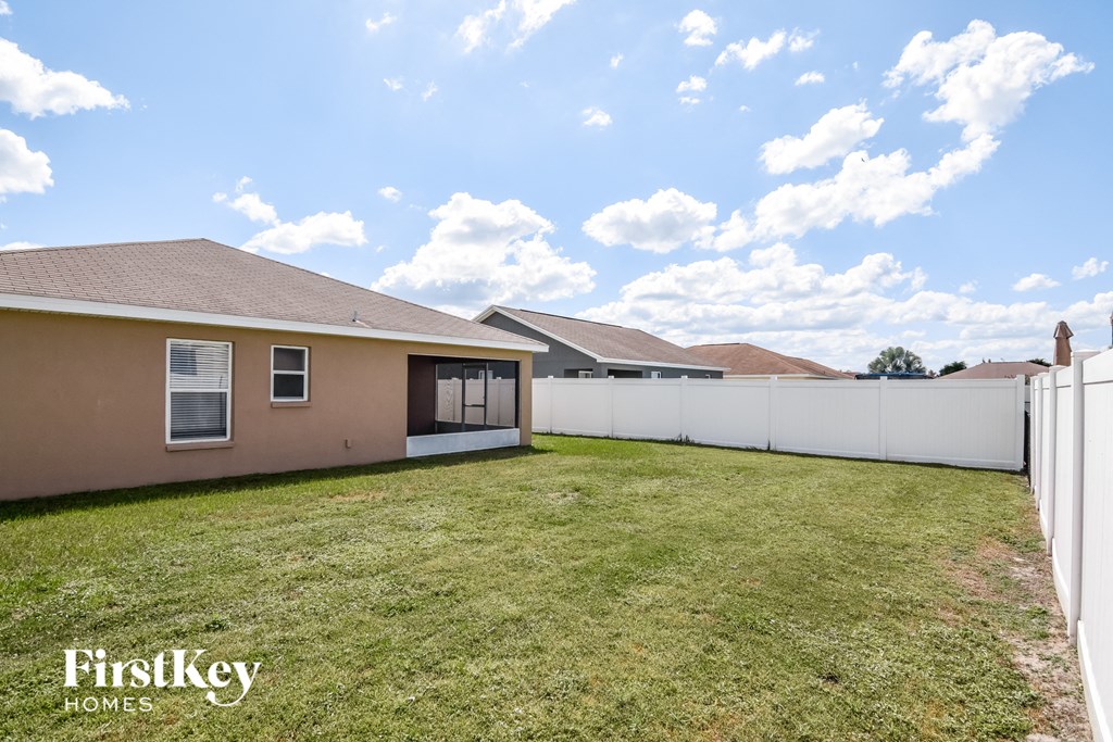 a backyard with a white fence and a house